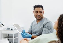 Profissional de saúde usa um tablet durante consulta e atendimento clínico.