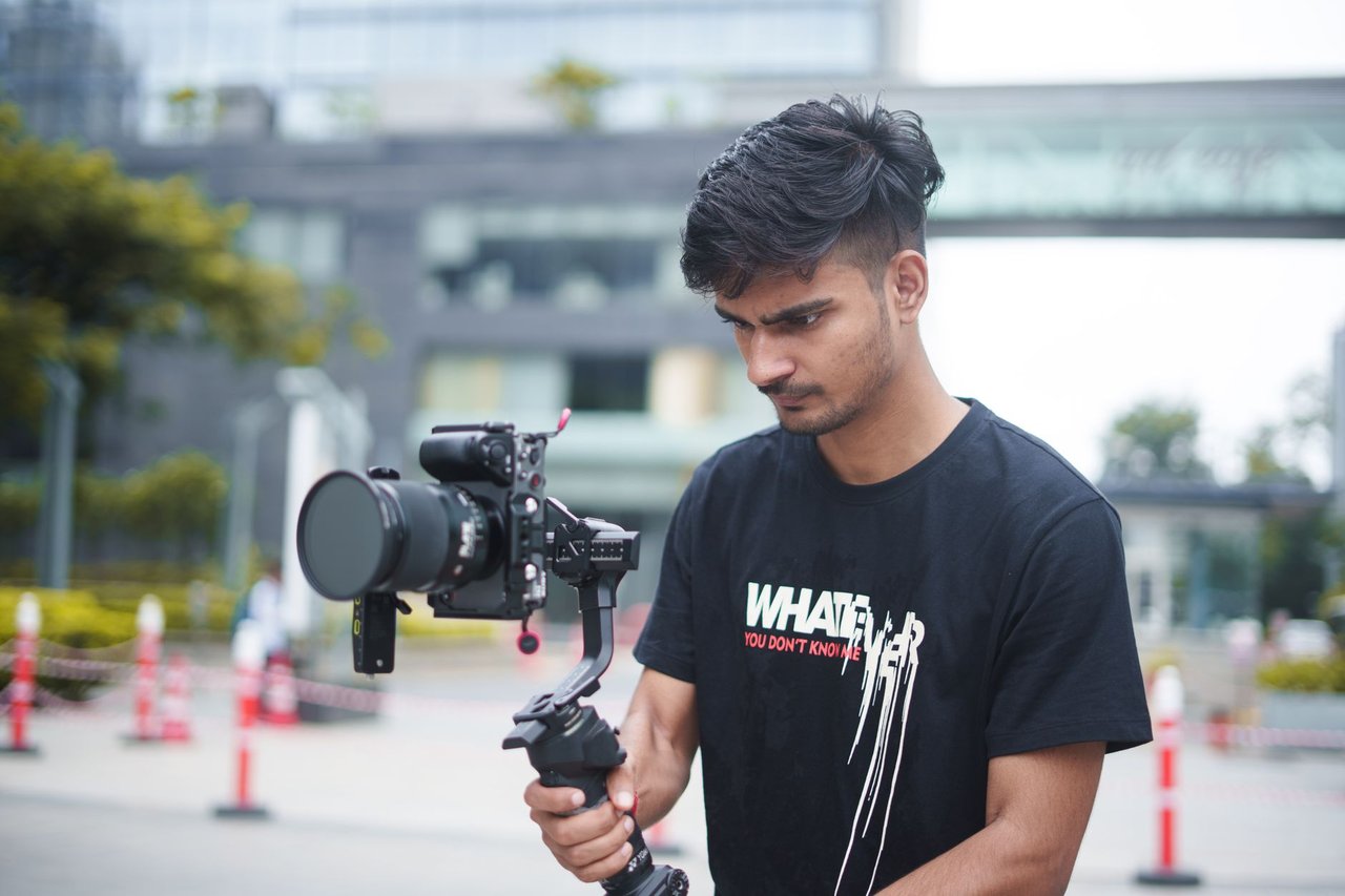 Jovem cineasta grava uma produção ao ar livre usando uma câmera acoplada a um gimbal.