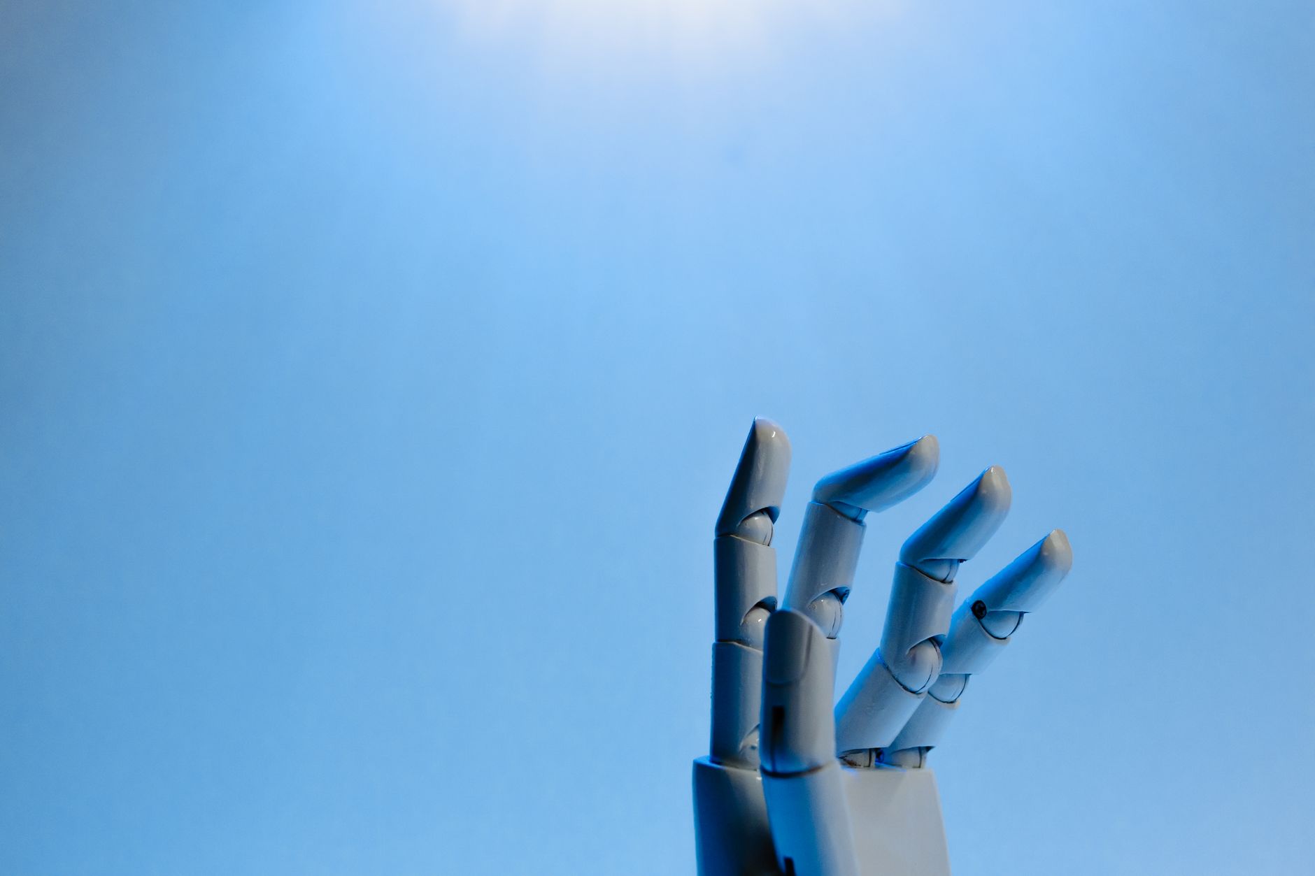 Mão robótica articulada estendida contra um fundo azul, em uma ilustração conceitual sobre inteligência artificial.
