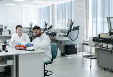 Equipe de pesquisadores analisa dados e equipamentos em um laboratório moderno.