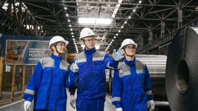 Trabalhadores usando equipamentos de segurança conversam dentro de uma fábrica siderúrgica.